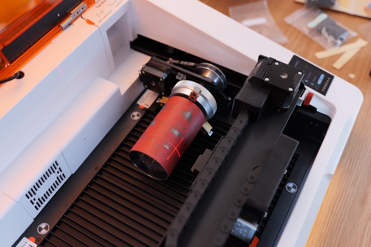 Trục xoay khắc vật thể tròn — laser căn tâm bằng chấm chữ thập đỏ.